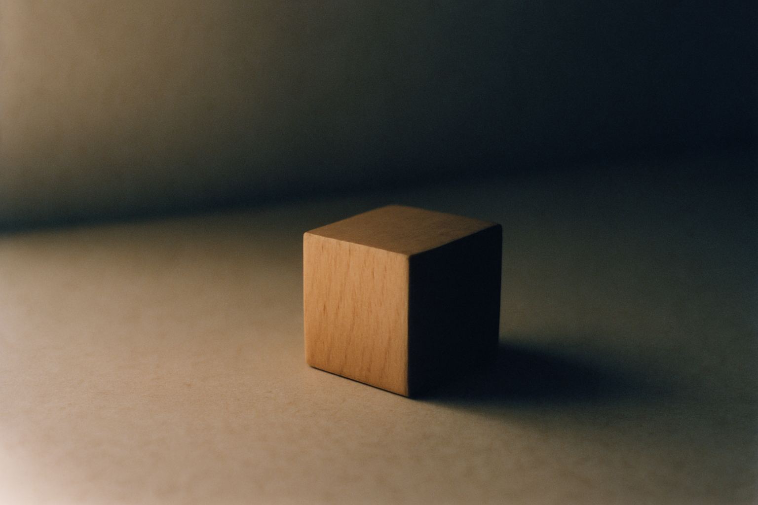 A single wooden block, one edge lit, the rest in shadow.